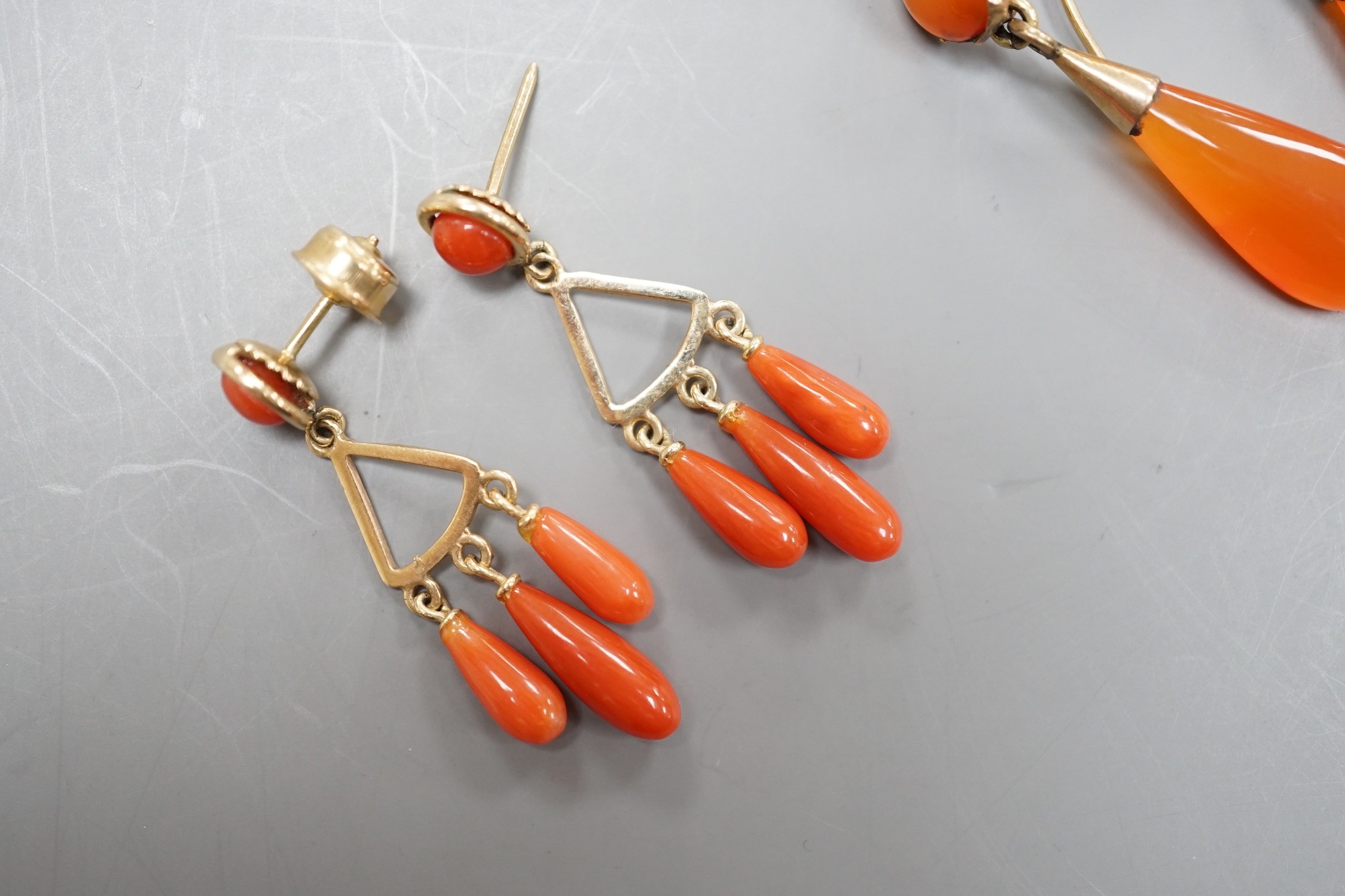 A pair of yellow metal and triple drop coral earrings, overall 37mm, gross 4.4 grams and a pair of carnelian set drop earrings.